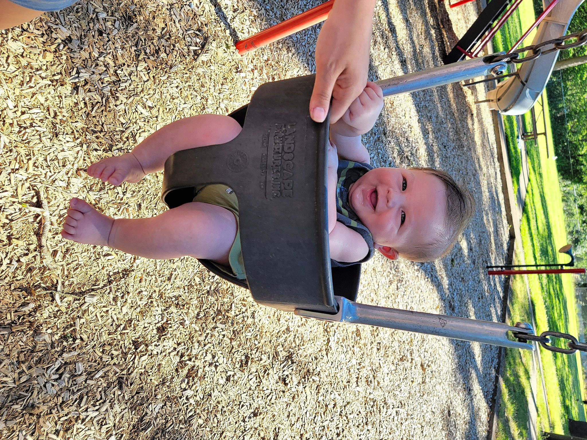 Alonzo is registered to the contest to win money with this photo: child, city, fun, grass, happy, hat, human_leg, leisure, outdoor_play_equipment, people_in_nature, person, plant, play, playground, recreation, smile, t_shirt, thigh, toddler, tree