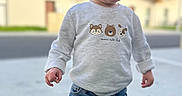 Leeroy a rejoint le concours — aidez-le/la à gagner de superbes lots ! toddler, child, curly_hair, sweater, animal_print, jeans, outdoor, grass, side_view, daylight, casual_clothing, cute, young_child, standing, expression, curious, blue_sky, background_building, portrait, person
