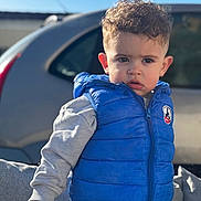 Leeroy a rejoint le concours — aidez-le/la à gagner de superbes lots ! toddler, child, boy, blue_vest, curly_hair, outdoor, car, daylight, casual_clothing, portrait, serious_expression, jacket, sweatshirt, person, young_child, nature, sunlight, vehicle, face, candid