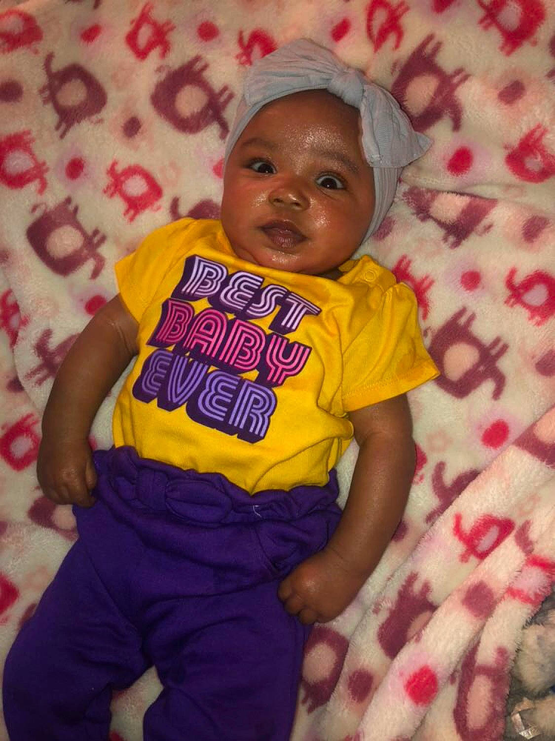 Malià is registered to the contest to win money with this photo: arm, baby, baby_products, baby_toddler_clothing, cap, child, face, fun, happy, linens, magenta, pattern, person, pink, purple, shorts, skin, sleeve, smile, t_shirt