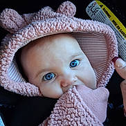 Scarlet is registered to the contest to win money with this photo: baby, blue_eyes, pink_clothing, hood, mitten, car_seat, child, infant, face, cute, close_up, apparel, warm_clothing, person, portrait, hand, seatbelt, warning_label, soft_texture, indoor