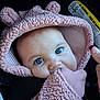 baby, blue_eyes, pink_clothing, hood, mitten, car_seat, child, infant, face, cute, close_up, apparel, warm_clothing, person, portrait, hand, seatbelt, warning_label, soft_texture, indoor