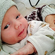 Aaron a rejoint le concours — aidez-le/la à gagner de superbes lots ! baby, infant, face, hat, hand, clothing, person, newborn, sleepy, cozy, knit, patterned, arm, indoor, human, cute, closeup, soft, resting, warm