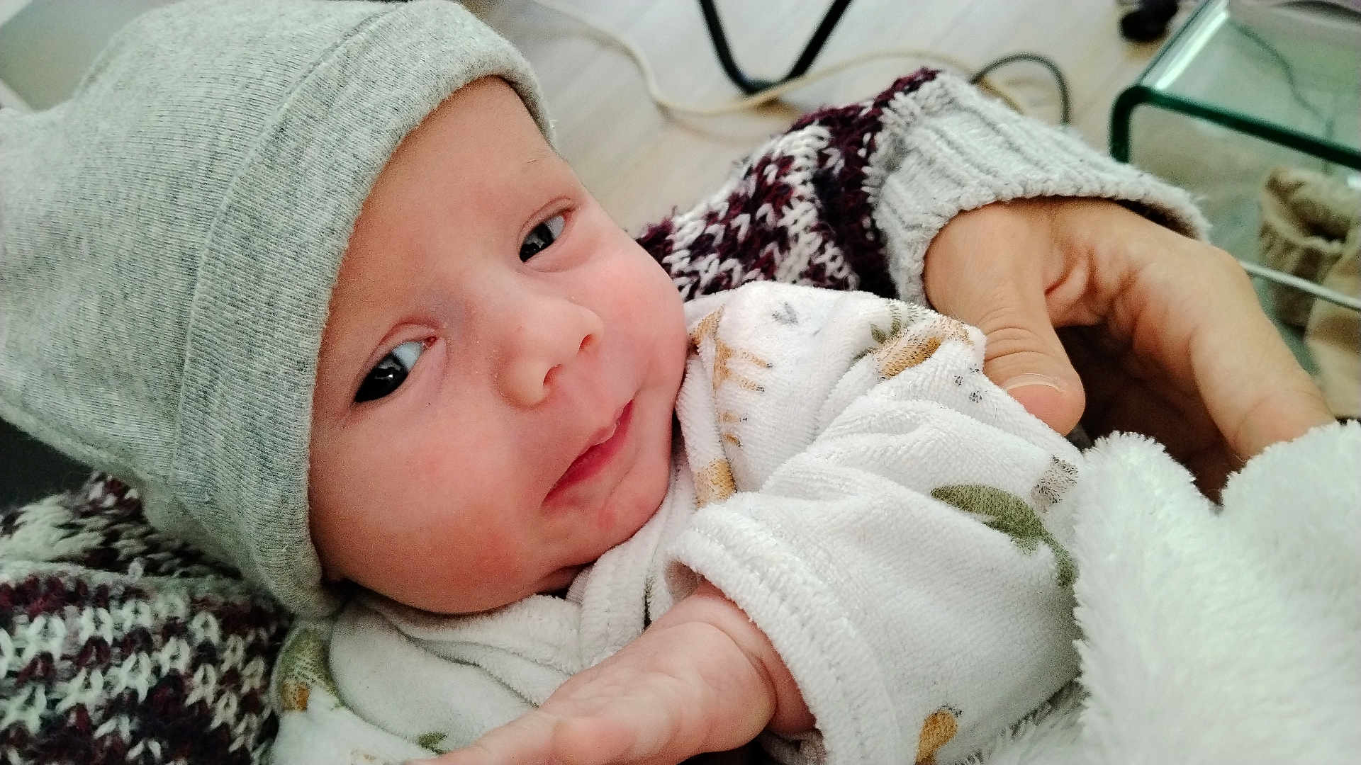 Aaron a rejoint le concours — aidez-le/la à gagner de superbes lots ! baby, infant, face, hat, hand, clothing, person, newborn, sleepy, cozy, knit, patterned, arm, indoor, human, cute, closeup, soft, resting, warm