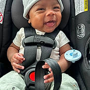 Jalen is registered to the contest to win money with this photo: baby, smiling, car_seat, seatbelt, infant, beanie, clothing, pacifier, hands, happy, child, cute, safety, straps, infant_clothing, portrait, closeup, seat, indoors, secure