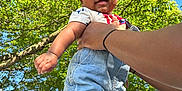 Jalen is registered to the contest to win money with this photo: baby, child, smiling, outdoor, hand, tree, greenery, sky, denim_shorts, shirt, footwear, socks, holding, person, happy, sunlight, daylight, nature, portrait, cute