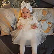 Amélia participe au concours pour gagner de l'argent avec cette photo : baby, infant, child, dress, headwrap, bow, pillow, cushion, sofa, living_room, portrait, cute, smile, shoes, tights, floral, lamp, plant, hands, fabric