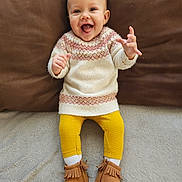 Amélia participe au concours pour gagner de l'argent avec cette photo : baby, blanket, boots, child, couch, cozy, cushion, cute, feet, hands, happy, indoor, infant, knitwear, legs, moccasins, portrait, smiling, sweater, yellow_leggings