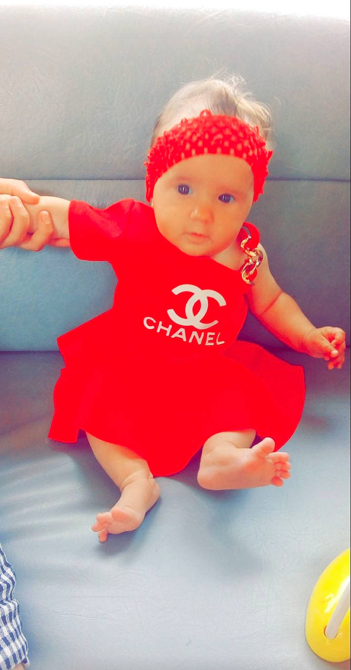 Djouliana a rejoint le concours — aidez-le/la à gagner de superbes lots ! baby, baby_toddler_clothing, cap, child, costume_hat, finger, flooring, fun, gesture, happy, hat, headgear, headwear, human_leg, magenta, one_piece_garment, person, pink, red, sleeve