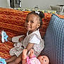 Tasnim participe au concours pour gagner de l'argent avec cette photo : child, girl, doll, couch, indoor, smiling, hair_bow, floral_dress, toy, blue_shoes, patterned_fabric, pillow, living_room, home, furniture, cute, portrait, sitting, young_child, happy