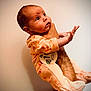 baby, infant, one_month, onesie, giraffe_print, hand, arm, person, portrait, curious, cute, newborn, indoor, skin, clothing, expression, human, child, holding, looking_up
