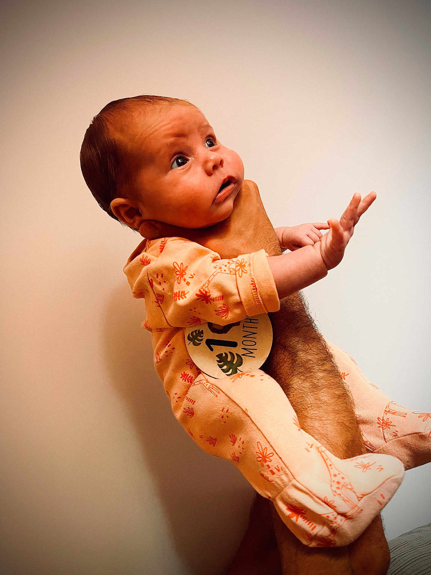 Zoé participe au concours pour gagner de l'argent avec cette photo : baby, infant, one_month, onesie, giraffe_print, hand, arm, person, portrait, curious, cute, newborn, indoor, skin, clothing, expression, human, child, holding, looking_up