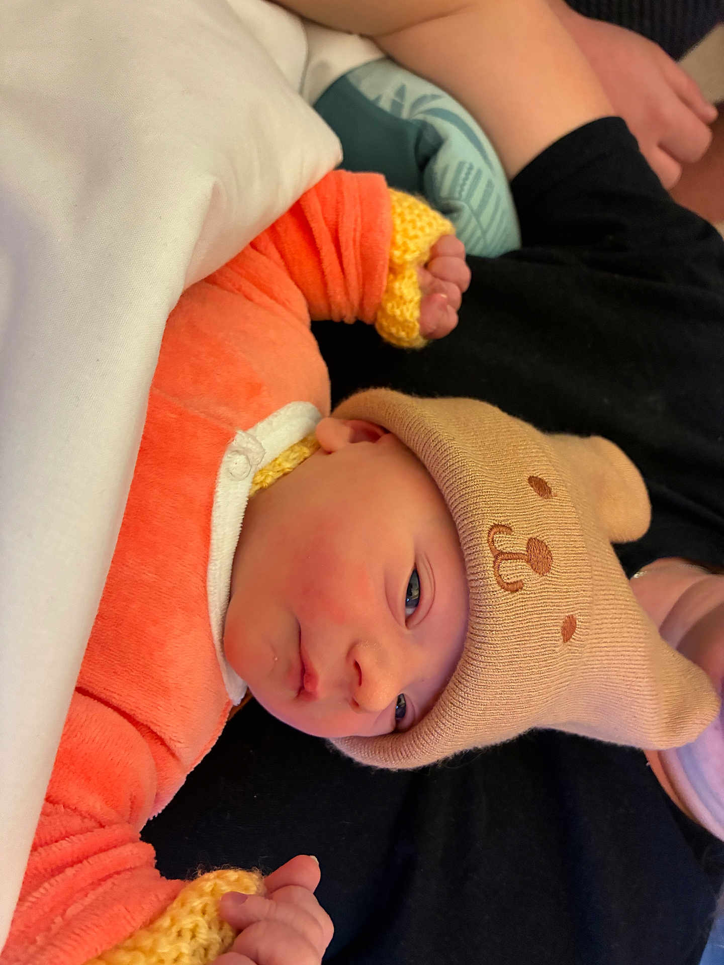 Siméo a rejoint le concours — aidez-le/la à gagner de superbes lots ! newborn, baby, infant, hat, knitwear, orange_clothing, sleepwear, hand, face, person, soft_texture, blanket, resting, cute, cozy, portrait, indoor, child, newborn_hat, warm_clothing