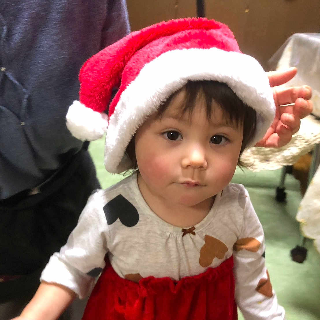 Kurumi joined the competition — help win amazing prizes! baby, child, toddler, santa_hat, christmas, holiday, portrait, indoor, smiling, facial_expression, dark_hair, brown_eyes, red_dress, festive_clothing, adult, hand, furniture, home, decorations, photography