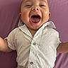 baby, child, smiling, happy, white_shirt, beige_pants, lying_down, purple_background, cute, infant, portrait, one_person, indoors, joyful, close_up, skin, face, mouth_open, expression, human