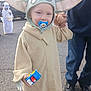 toddler, baby_yoda_costume, pacifier, toy, hand_holding, child, ghost_costume, bucket, halloween, street, sidewalk, adult, costume, cute, outdoor, daylight, person, footwear, clothing, smile