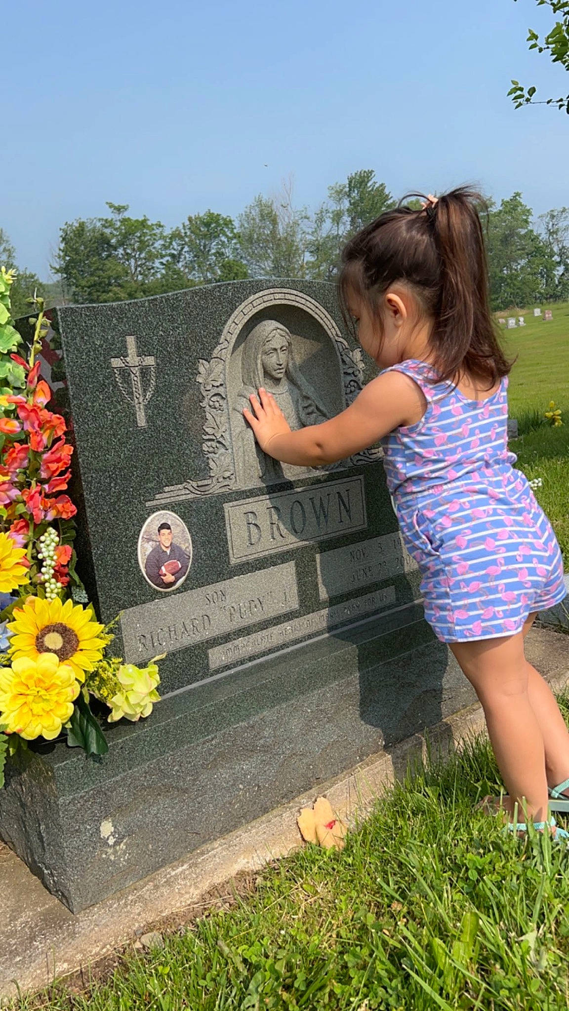 Addie is registered to the contest to win money with this photo: annual_plant, cemetery, flower, flower_arranging, garden, grass, grave, happy, headstone, leaf, leisure, people_in_nature, person, plant, rose, shrub, sky, spring, summer, toddler