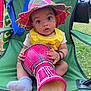 Kalycia participe au concours pour gagner de l'argent avec cette photo : baby, child, hat, yellow_overalls, drum, musical_instrument, green_chair, outdoor, grass, sock, curious, person, seated, colorful, woven_hat, hand, expression, bracelet, nature, daylight