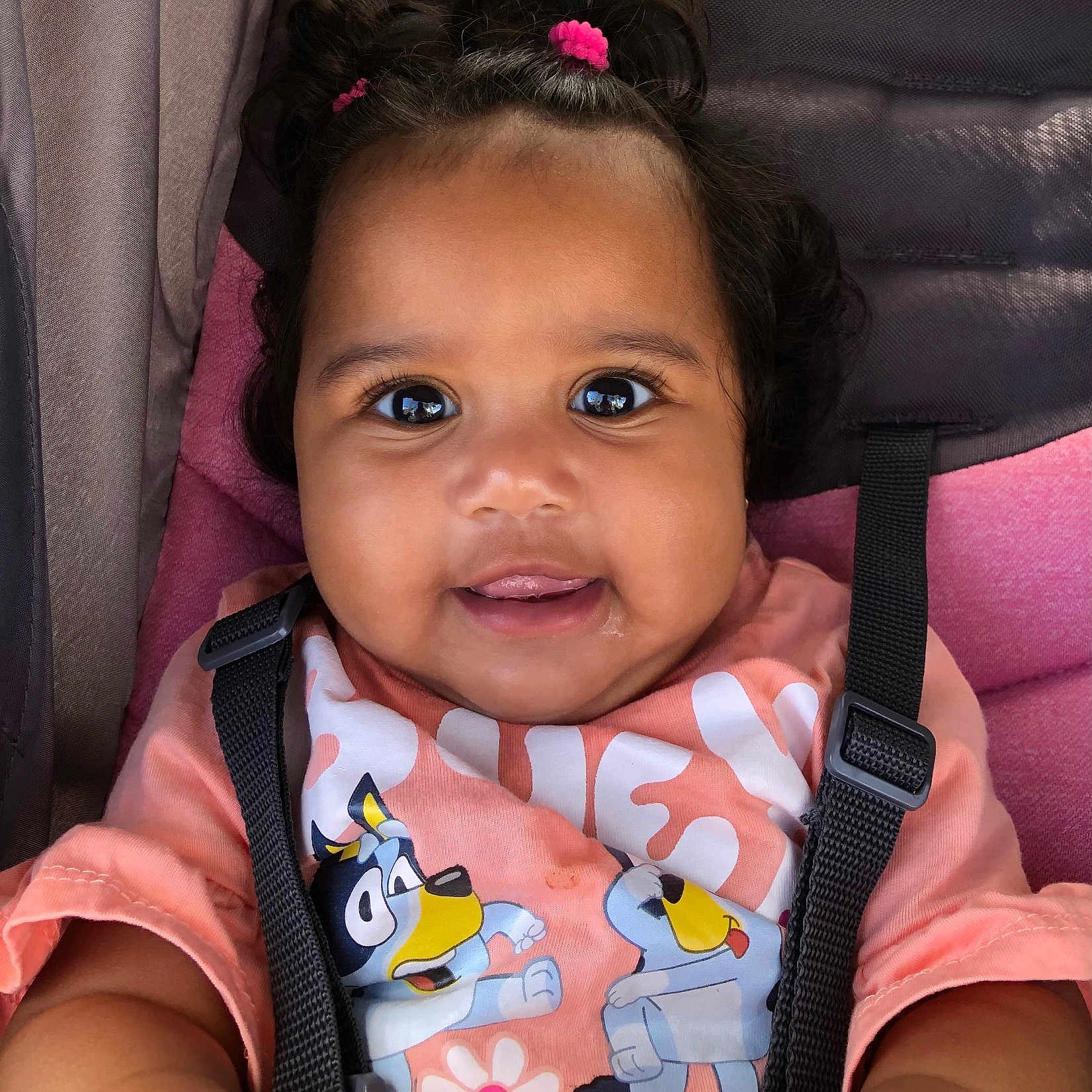 A Riyah Hall joined the competition — help win amazing prizes! baby, child, smiling, face, hair, pink, shirt, cartoon, seatbelt, car_seat, straps, cute, happy, skin, person, indoors, closeup, infant, hair_tie, playful