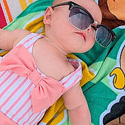 Lainey joined the competition — help win amazing prizes! baby, child, sunglasses, swimsuit, pink_bow, striped_clothing, towel, colorful, outdoor, relaxing, cute, infant, summer, fashion, portrait, skin, arm, head, face, laying_down