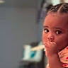 toddler, child, indoors, floor, pajamas, braided_hair, thumb_sucking, curious, young_child, person, home, cozy, seated, expression, casual_clothing, infant, baby, portrait, cute, looking