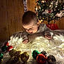 baby, blanket, celebration, child, christmas_lights, christmas_tree, cute, decorations, festive, festivity, holiday, holiday_decor, holiday_spirit, indoor, infant, ornaments, smiling, snowman_decoration, warm_lighting, wood_paneling