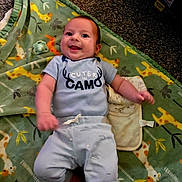 Kolten joined the competition — help win amazing prizes! baby, smiling, infant, blanket, animal_pattern, pacifier, carpet, clothing, cute, lying_down, happy, face, blue_pants, onesie, indoors, child, soft_texture, playful, young, expression