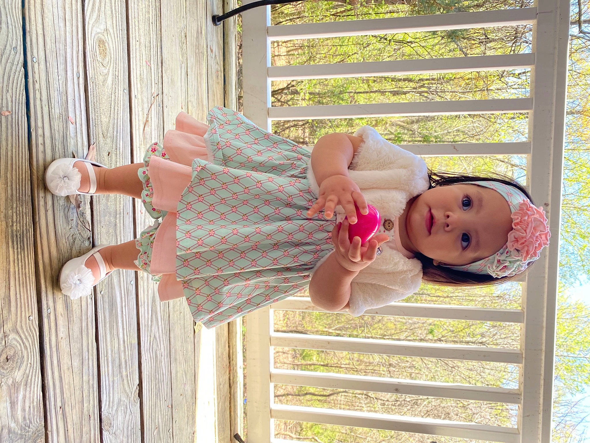 Zelah is registered to the contest to win money with this photo: arm, baby_toddler_clothing, clothing, dress, eye, face, facial_expression, finger, grass, hand, happy, head, headwear, human_body, people_in_nature, person, pink, plant, skin, tree