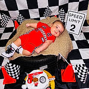 Eleggúasdiel joined the competition — help win amazing prizes! baby, birthday, black_and_white, cake, celebration, checkered_flag, decorations, footwear, indoor, infant, orange_cone, person, plush_cushion, portrait, racing_theme, red_clothing, smiling, speed_limit_sign, tire, toy