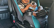 Yemi joined the competition — help win amazing prizes! child, toddler, smiling, car, car_seat, safety_harness, vehicle_interior, travel, road_trip, bottle, shorts, shoes, hair, portrait, seated, indoors, sunlight, window, trees, happy