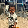 Yemi joined the competition — help win amazing prizes! child, toddler, boy, portrait, standing, indoor, waiting_area, chairs, tiled_floor, white_shirt, black_pants, curly_hair, facial_expression, looking_at_camera, toy, orange_object, hyundai, glass_windows, furniture, candid_photo