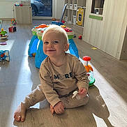 Giulio a rejoint le concours — aidez-le/la à gagner de superbes lots ! toddler, child, smiling, indoor, playroom, toy, pacifier, wooden_floor, clothing, furniture, sunlight, shadow, happy, blond_hair, sitting, baby, cute, home, floor, young_child