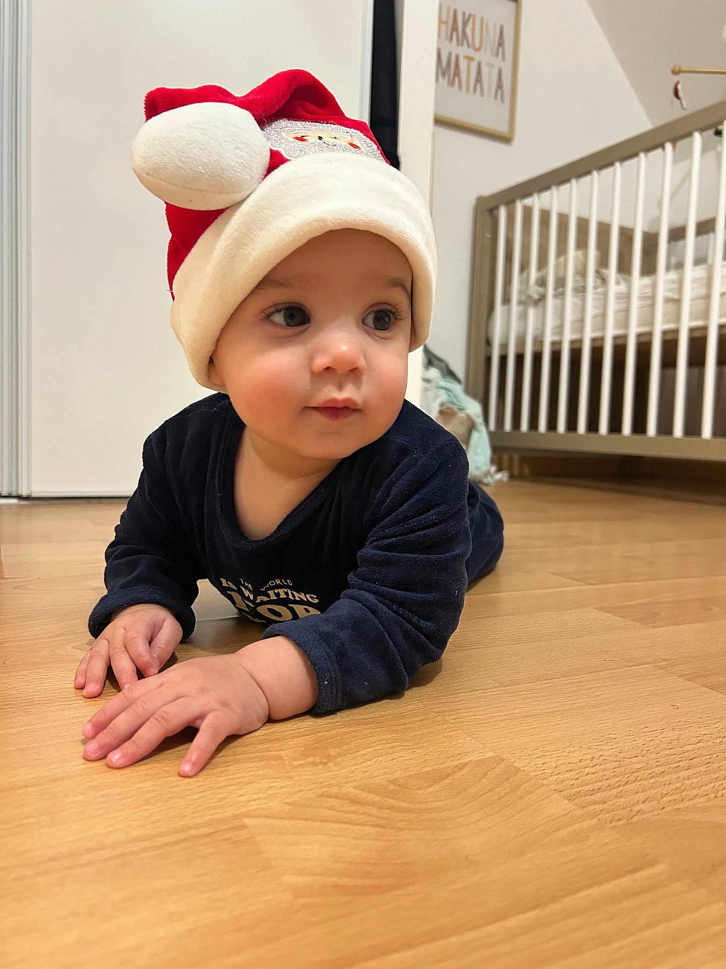 Maël a rejoint le concours — aidez-le/la à gagner de superbes lots ! baby, child, santa_hat, floor, wooden_floor, crib, nursery, framed_artwork, hakuna_matata, indoor, clothing, long_sleeve, person, cute, holiday, festive, portrait, crawling, expression, home
