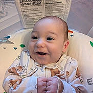 Oliver joined the competition — help win amazing prizes! baby, infant, smiling, onesie, hands, clenched_fists, bassinet, warning_label, mesh_side, cute, happy, face, clothing, indoor, child, newborn, portrait, baby_bedding, baby_garment, sleepwear