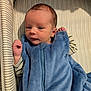 Noah is registered to the contest to win money with this photo: baby, newborn, infant, sleeping_sack, blue_clothing, striped_bassinet, face, hand, eyes, cozy, indoor, portrait, cute, small, child, soft, fabric, sleepwear, lying_down, resting
