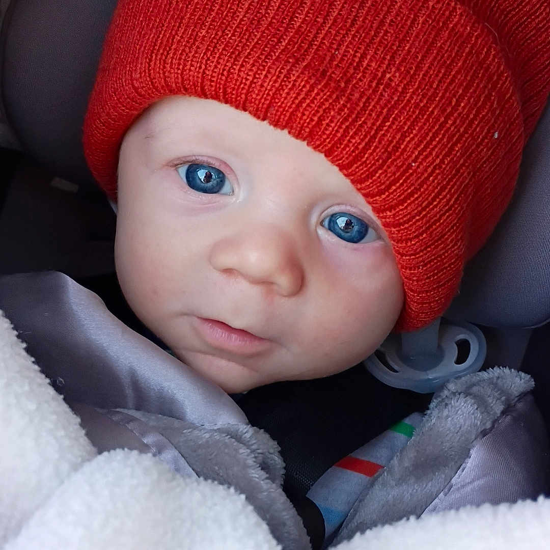 Elvis joined the competition — help win amazing prizes! baby, blanket, blue_eyes, bundle, car_seat, child, close_up, cozy, cute, face, headwear, indoor, infant, knit_hat, orange_hat, portrait, sleepy, soft_texture, warm, young_child