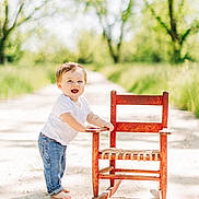 Turner joined the competition — help win amazing prizes! toddler, child, rocking_chair, barefoot, smiling, outdoor, path, trees, greenery, sunlight, jeans, white_shirt, happy, nature, daylight, portrait, playing, young_child, casual, summer