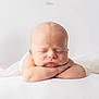baby, newborn, sleeping, arms_folded, blanket, white_background, peaceful, infant, cute, portrait, skin, head, face, closed_eyes, soft_texture, resting, tender, young, child, studio_photo