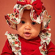Navayla is registered to the contest to win money with this photo: adorable, baby, background, bow, child, closeup, cute, expression, eyes, face, fashion, floral, hat, headwear, infant, portrait, red_clothing, smile, warm_colors, young