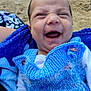 baby, infant, smile, laughing, blue_vest, knitted_clothing, blanket, beach, sand, happy, child, portrait, cute, person, mohaawk, outdoor, young, expression, warm_clothing, hand