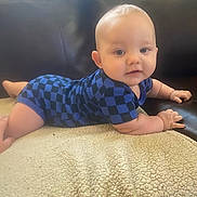 Dakota is registered to the contest to win money with this photo: baby, child, infant, blue_clothing, checkered, blanket, couch, leather, skin, face, eyes, hands, arms, smiling, lying_down, indoors, soft_texture, cute, young, portrait