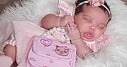 Jalaya is registered to the contest to win money with this photo: baby, sleeping, pink_dress, headband, flower, pearl_necklace, purse, fluffy_rug, cute, infant, peaceful, hand, closed_eyes, soft_texture, adorable, portrait, child, resting, indoor, newborn