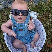 Carter is registered to the contest to win money with this photo: baby, sunglasses, denim_overalls, basket, grass, rocks, outdoor, infant, cute, child, fashion, summer, casual, headwear, person, legs, feet, hand, expression, accessory