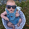 baby, sunglasses, denim_overalls, basket, grass, rocks, outdoor, infant, cute, child, fashion, summer, casual, headwear, person, legs, feet, hand, expression, accessory
