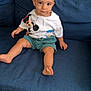 toddler, child, blue_couch, mickey_mouse, donald_duck, tshirt, shorts, barefoot, smiling, sitting, indoors, tile_floor, hair, face, person, young_child, casual_clothing, furniture, home, cute