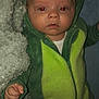 baby, infant, dinosaur_onesie, green_clothing, blanket, red_eye, cute, child, portrait, indoor, soft_texture, cozy, sleepwear, hooded_outfit, small_hand, lying_down, face, person, expressionless, newborn