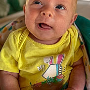 Rogan joined the competition — help win amazing prizes! baby, infant, yellow_shirt, easter, cute, smiling, portrait, child, clothing, hands, face, eyes, skin, expression, indoors, blanket, colorful, comfort, happy, young