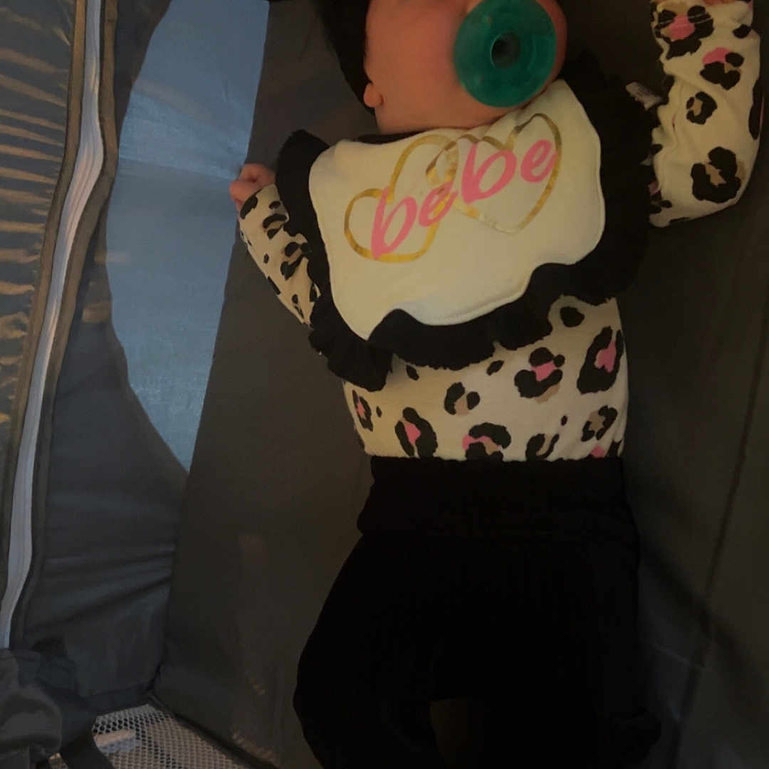 Rayann joined the competition — help win amazing prizes! baby, bib, black_pants, bow, child, clothing, curious, cute, foot, hand, headband, indoors, infant, leopard_print, lying_down, mesh, pacifier, playpen, soft_lighting, white_top