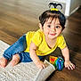 toddler, child, yellow_shirt, blue_jeans, toy_keys, wooden_floor, white_rug, hair_tie, pony_tail, smiling, indoors, cute, playful, happy, baby, crawling, curious, bright_eyes, small_hands, floor