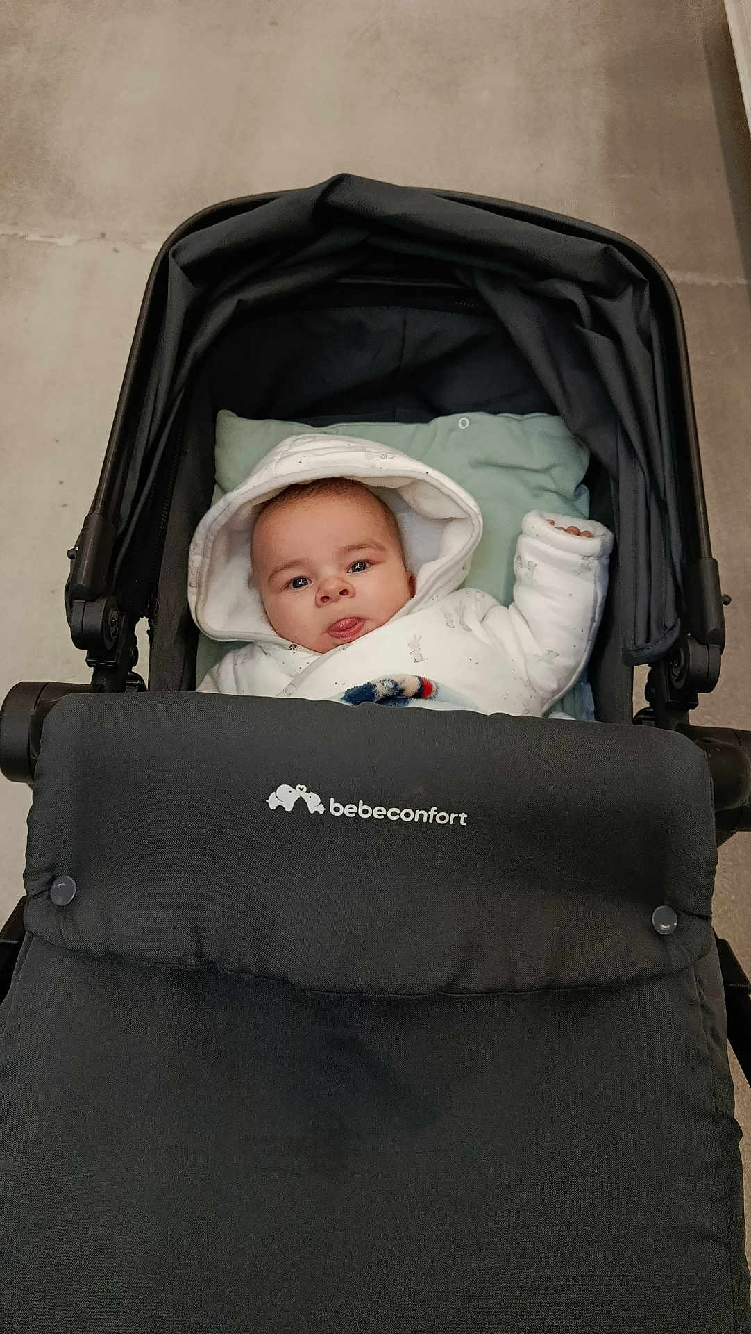 Zayon a rejoint le concours — aidez-le/la à gagner de superbes lots ! baby, infant, stroller, pram, hood, onesie, blanket, face, tongue, eyes, cute, portrait, sitting, padded_seat, handle, indoor, floor, bebeconfort, cozy, clothing